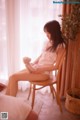 A woman sitting on a chair holding a teddy bear.