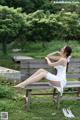 A woman in a white dress sitting on a wooden bench.