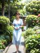 A woman in a blue dress walking down a sidewalk.