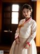 A woman in a white hanbok is posing for a picture.