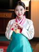 A woman in a blue and white hanbok poses for a picture.