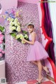 A woman in a pink dress holding a bouquet of flowers.