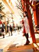 A woman in a white coat is walking down the street.