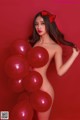 A naked woman holding a bunch of red balloons.