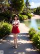 A woman in a red dress walking down a path next to a river.