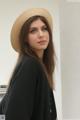 A woman wearing a straw hat standing in front of a wall.