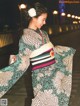 A woman in a kimono walking down a street at night.