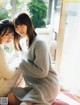 A couple of women sitting next to each other on a bed.