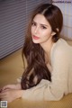 A woman with long brown hair laying on a bed.