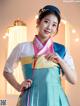 A woman in a blue and pink hanbok poses for a picture.