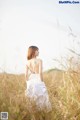 A woman in a white dress standing in a field.