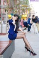 A woman in a blue suit sitting on a bench.