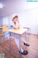 A woman sitting at a desk in a classroom.