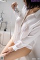 A woman in a white shirt is taking a shower.